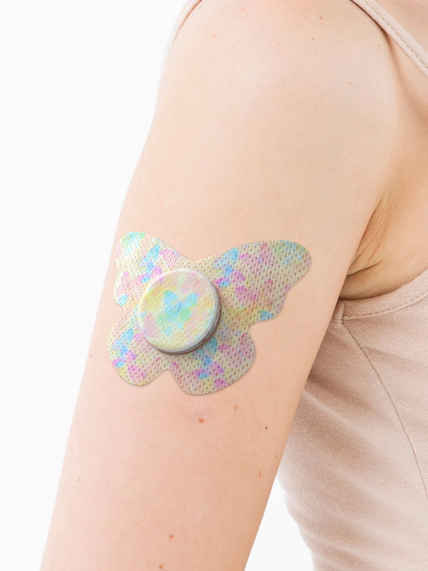 FreeStyle Libre 2 butterfly shape patch close-up on arm, showing breathable adhesive support around the sensor
